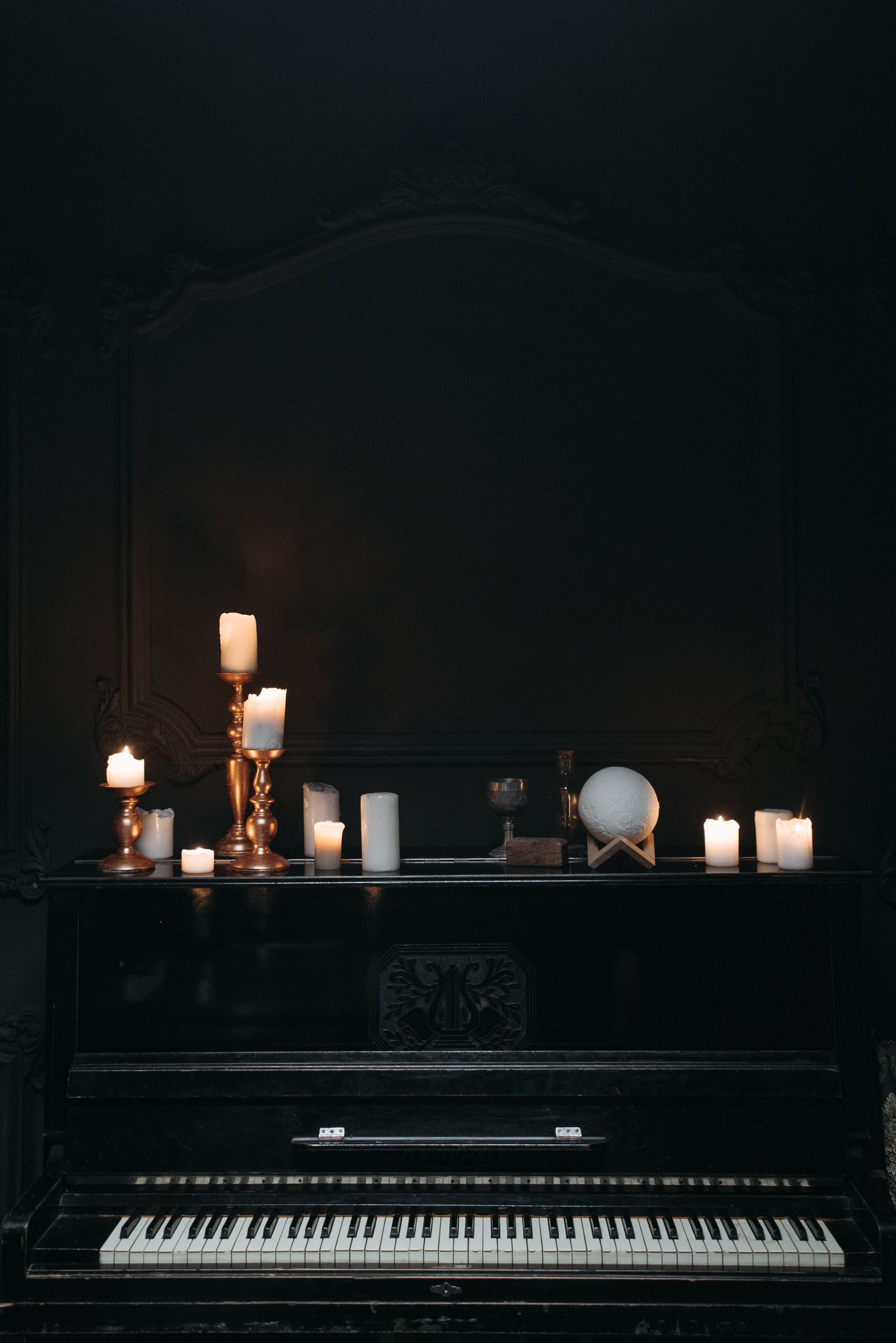 A dark, moodily-lit piano adorned with candles for a classic ambiance.