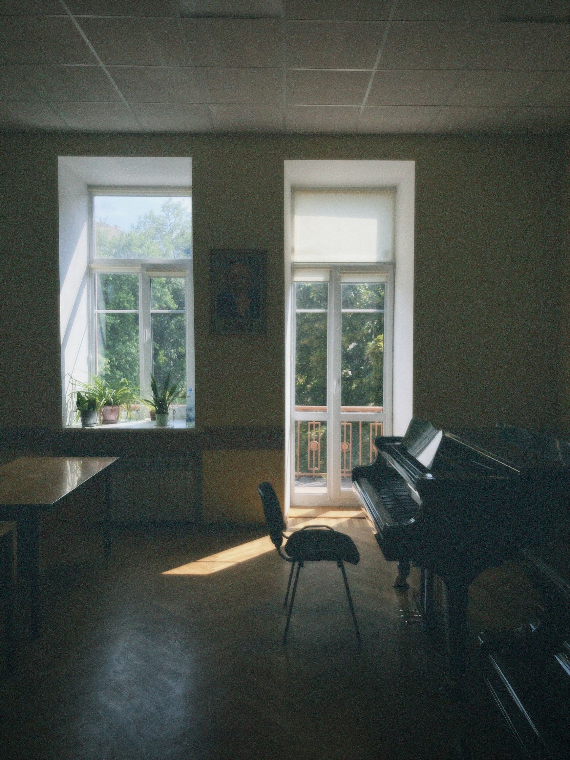 A peaceful classroom with a grand piano and sunlight streaming through large windows.